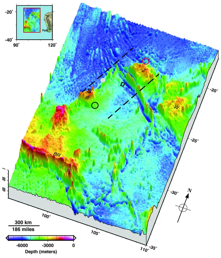 Seafloor topography in the Malaysia Airlines flight MH370 search area. Dashed lines approximate the search zone for sonar pings emitted by the flight data recorder and cockpit voice recorder popularly called black boxes. The first sonar contact (black circle) was reportedly made by a Chinese vessel on the east flank of Batavia Plateau (B), where the shallowest point in the area (S) is at an estimated depth of 1637 meters. The next reported sonar contact (red circle) was made by an Australian vessel on the north flank of Zenith Plateau (Z). The deepest point in the area (D) lies in the Wallaby-Zenith Fracture Zone at an estimated depth of 7883 meters. The Wallaby Plateau (W) lies to the east of the Zenith Plateau. The shallowest point in the entire area shown here is on Broken Ridge (BR). Deep Sea Drilling Project (DSDP) site 256 is marked by a gray dot. The inset in the top left shows the area’s location to the west of Australia. Seafloor depths are from the General Bathymetric Chart of the Oceans [2010]. Credit: Walter H.F. Smith and Karen M. Marks