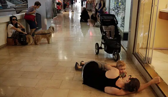 A woman lies with her baby on the floor of a shopping mall as an air-raid siren, warning of incoming rockets, sounds in Tel Aviv, July 10, 2014. (photo by REUTERS/Daniel Bar-On) 