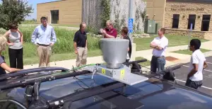 Event attendees gather around a sedan outfitted with a spinning LiDAR sensor. (Photo by Micheal Foley, MnDOT)